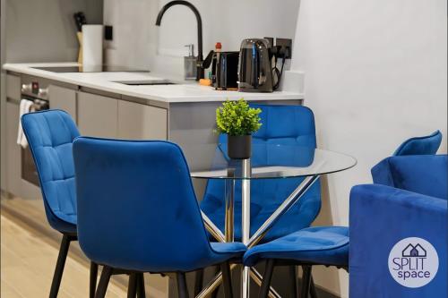 a kitchen with blue chairs and a glass table at Free Parking - Next to Waitrose - Finchley 2Bed2BA in Finchley