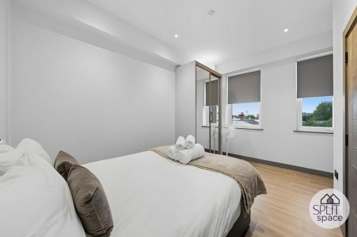 a white bedroom with a large bed and two windows at Free Parking - Next to Waitrose - Finchley 2Bed2BA in Finchley