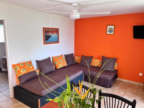 a couch in a living room with an orange wall at Cosy T2 dans village de pêcheurs, plage à pied in Sainte-Luce