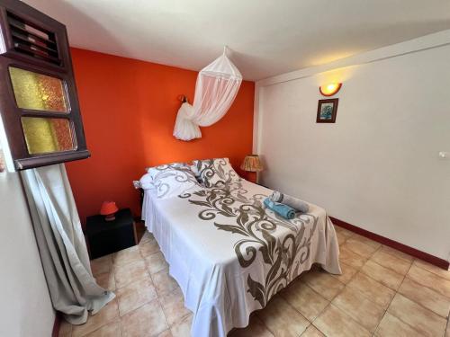 a bedroom with a bed and an orange wall at Cosy T2 dans village de pêcheurs, plage à pied in Sainte-Luce