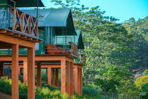 a green house with a balcony on top of it at Train View Chalet in Bandarawela