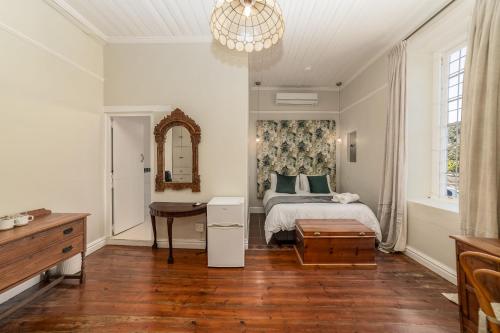 a bedroom with a bed and a table and a mirror at Nantes-vue in Paarl