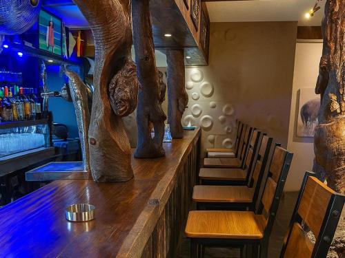 a bar with a wooden counter with wooden chairs at Echo Mountain Inn in Thabazimbi