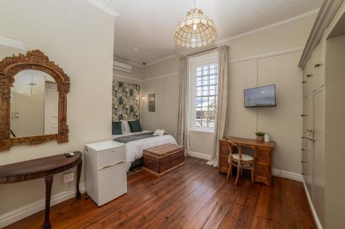 a bedroom with a bed and a desk and a mirror at Nantes-vue in Paarl