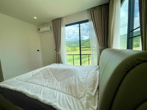 a bedroom with a bed and a large window at Cloud N Wind Khao Kho Thailand in Ban Lao Kok Kho