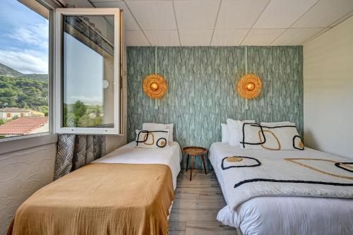two beds in a room with a window at Contact Hôtel Le Provence in Gémenos