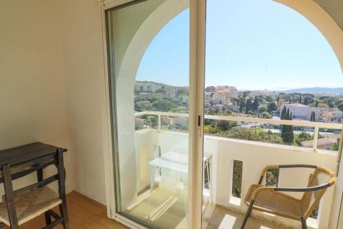 a room with a large window with a table and a chair at Hôtel Paradis in Bormes-les-Mimosas