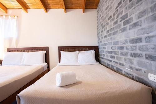 two beds in a room with a brick wall at Hospedaje La Quebrada in Máncora