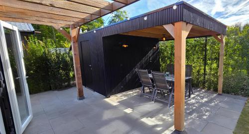 a wooden pavilion with a table and chairs on a patio at Luxe Natuurhuis Veluwe Home 'De Bosvogel' in Ermelo