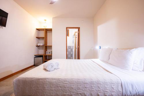 a bedroom with a white bed with two towels on it at Hospedaje La Quebrada in Máncora