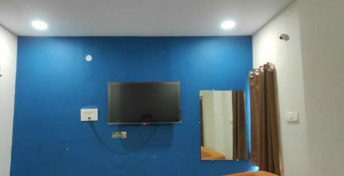 a bathroom with a blue wall with a tv on the wall at Hotel zova in Karīmnagar