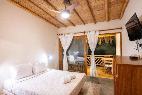 a bedroom with a bed and a television and a balcony at Hospedaje La Quebrada in Máncora