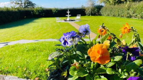 a garden with flowers and a cross in the background at Lissanisky House in Ballymackey
