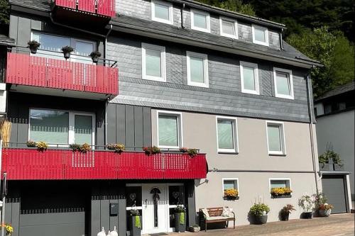 Una casa grande con balcones rojos en una calle. en Upland-Flair Ferienwohnung ABENDROT im Zentrum!, en Willingen