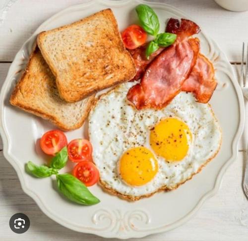a plate with eggs bacon tomatoes and toast at Sparta Patong in Ban Nong Chaeng