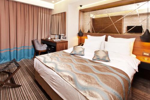 a hotel room with a large bed and a desk at Artur Hotel in Canakkale