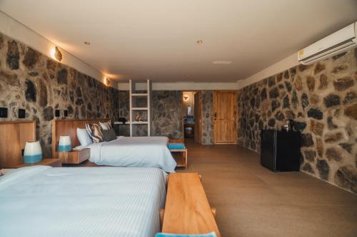 a bedroom with two beds and a stone wall at Perla Roca Hotel Boutique - Beach Front in Santa Marta