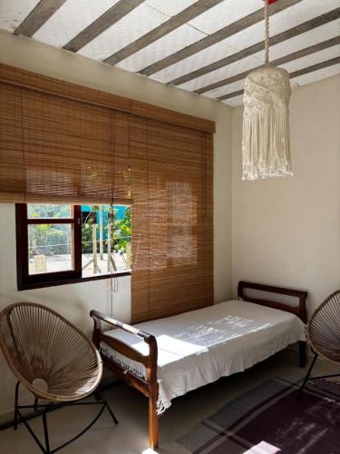 a bedroom with a bed and two chairs and a chandelier at Chalé Água viva in Paraty