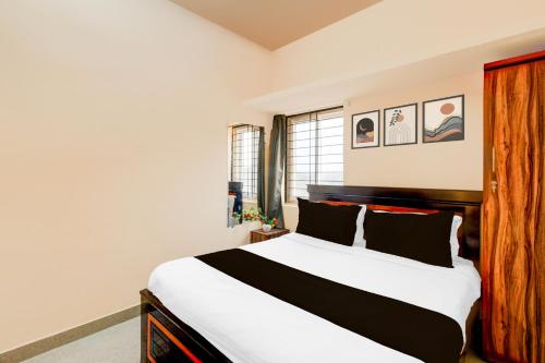 a bedroom with a large white bed with black pillows at Hotel O Blue Petals in Hyderabad