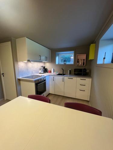 Una cocina con gabinetes blancos y una mesa y sillas. en Modern basement apartment, en Stavanger