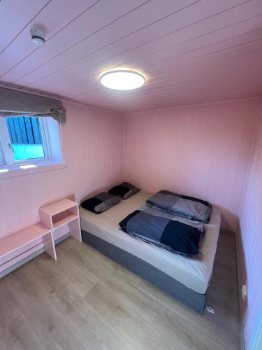 Una pequeña habitación con una cama y una ventana. en Modern basement apartment, en Stavanger