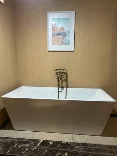 a white bath tub in a bathroom with a picture on the wall at Modern apartment near AUC - 3BR in Cairo