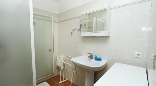 a white bathroom with a sink and a shower at La Ferme Des Rosières - Chambres in La Garde-Adhémar