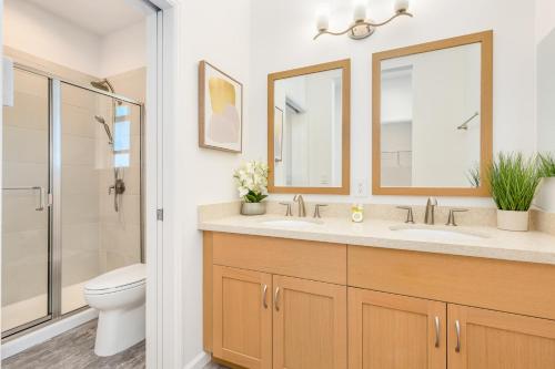 a bathroom with a sink and a toilet and a mirror at Kalo Homes Tropical Palm Getaway in Makaha Valley