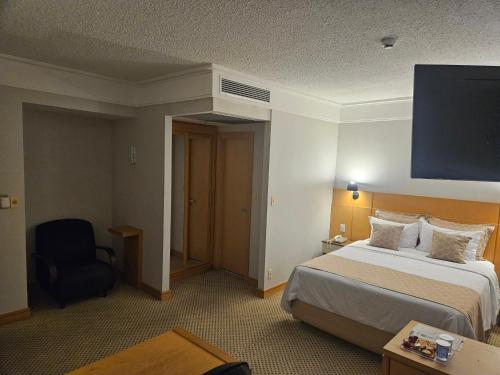 a hotel room with a bed and a chair at Flat Hotel Slaviero Guarulhos in Guarulhos