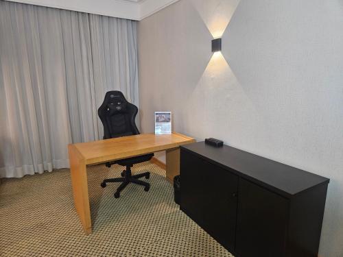 a desk with a black chair sitting next to a table at Flat Hotel Slaviero Guarulhos in Guarulhos