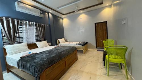 a bedroom with two beds and a yellow chair at Hampi Palace in Hampi