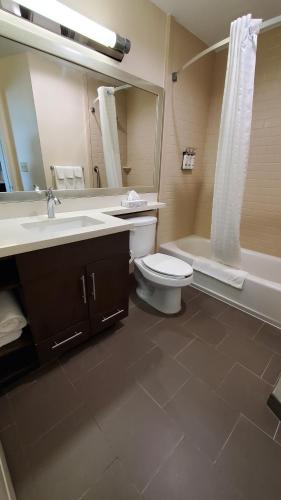 a bathroom with a toilet and a sink and a tub at Candlewood Suites - Lake Charles South by IHG in Lake Charles
