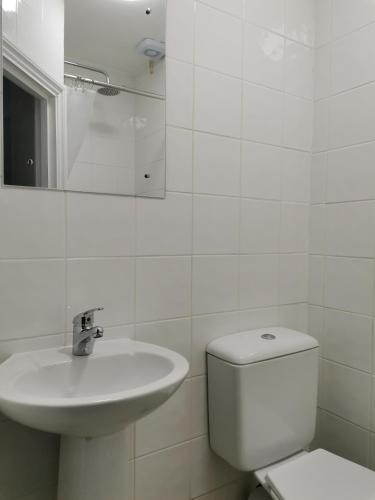 a white bathroom with a toilet and a sink at Chiswick Court Hotel in London