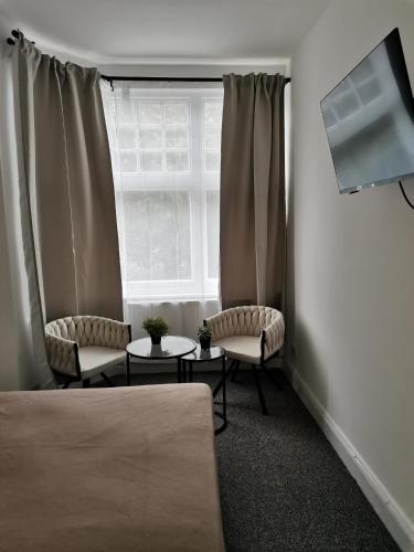 a room with two chairs and a window at Chiswick Court Hotel in London