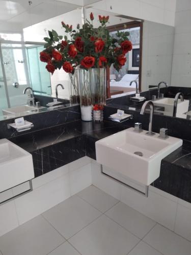 a bathroom with a sink and a vase of red roses at Palmares Hotel in Guaíra