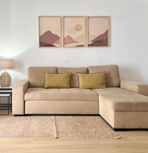 a couch in a living room with paintings on the wall at Canaryislandshost l Sal de Mar in Puerto del Carmen