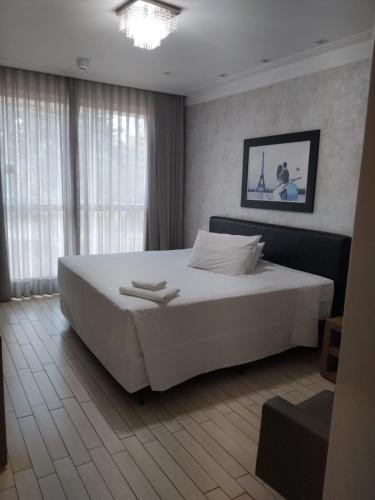 a bedroom with a large white bed and a window at Palmares Hotel in Guaíra