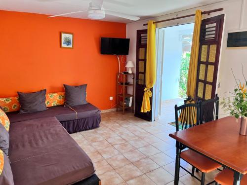 a living room with orange walls and a couch and a table at Cosy T2 dans village de pêcheurs, plage à pied in Sainte-Luce