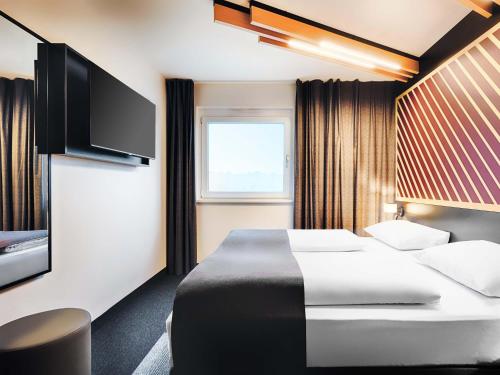 a hotel room with a bed and a flat screen tv at B&B HOTEL Wiesbaden-Hbf in Wiesbaden