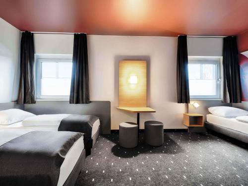 a hotel room with two beds and a couch at B&B HOTEL Wiesbaden-Hbf in Wiesbaden