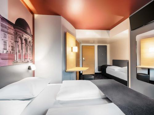 a hotel room with two beds and a tv at B&B HOTEL Wiesbaden-Hbf in Wiesbaden