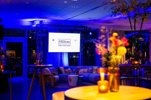 a living room with a couch and a big screen at Haven Hotel Rotterdam, Curio Collection by Hilton in Rotterdam