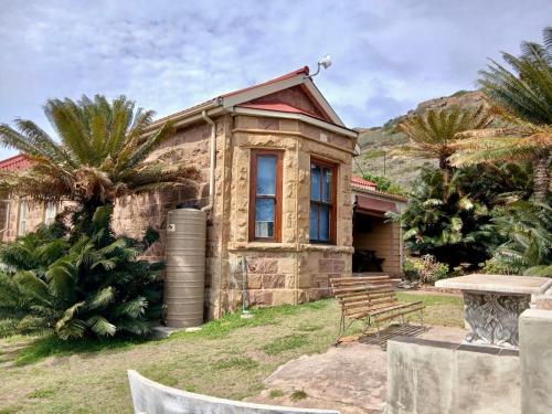 a stone house with a bench in front of it at Mossel Bay Self-Catering in Mossel Bay