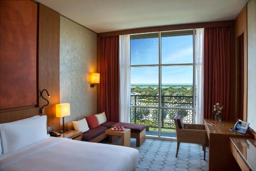 a hotel room with a bed and a couch and a window at Yas Plaza Marina by IHG in Abu Dhabi