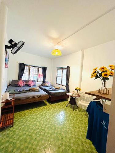 a living room with two beds and a green floor at Lungkluay homestay in Ko Kood