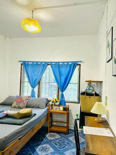 a bedroom with a bed with blue curtains and a table at Lungkluay homestay in Ko Kood