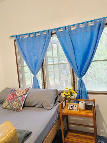 a bedroom with a bed and a window with blue curtains at Lungkluay homestay in Ko Kood