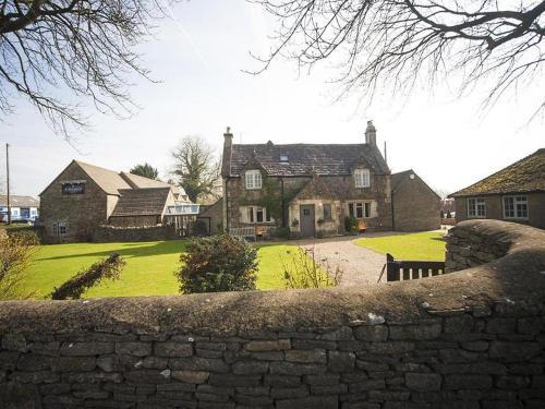 a stone wall in front of a house at The Ragged Cot in Minchinhampton