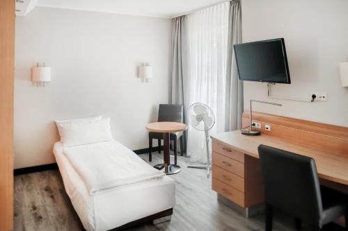 a hotel room with a bed and a desk with a tv at Garner Hotel Bremen North by IHG in Bremen
