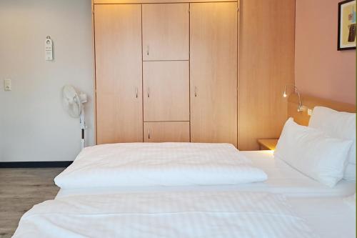 a bedroom with a white bed and a wooden cabinet at Garner Hotel Bremen North by IHG in Bremen